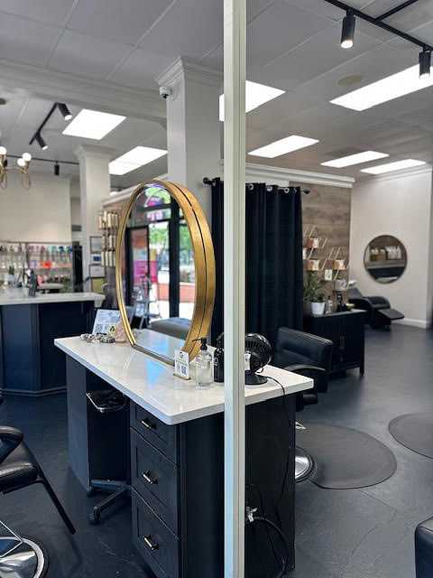 Modern salon interior with styling stations, mirrors, and product shelves, featuring chic decor.